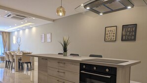 A modern kitchen with a central island, built-in oven, and dining area with chairs and a table.