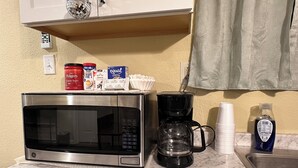 Una encimera de cocina con un microondas, una cafetera y varios utensilios de cocina.