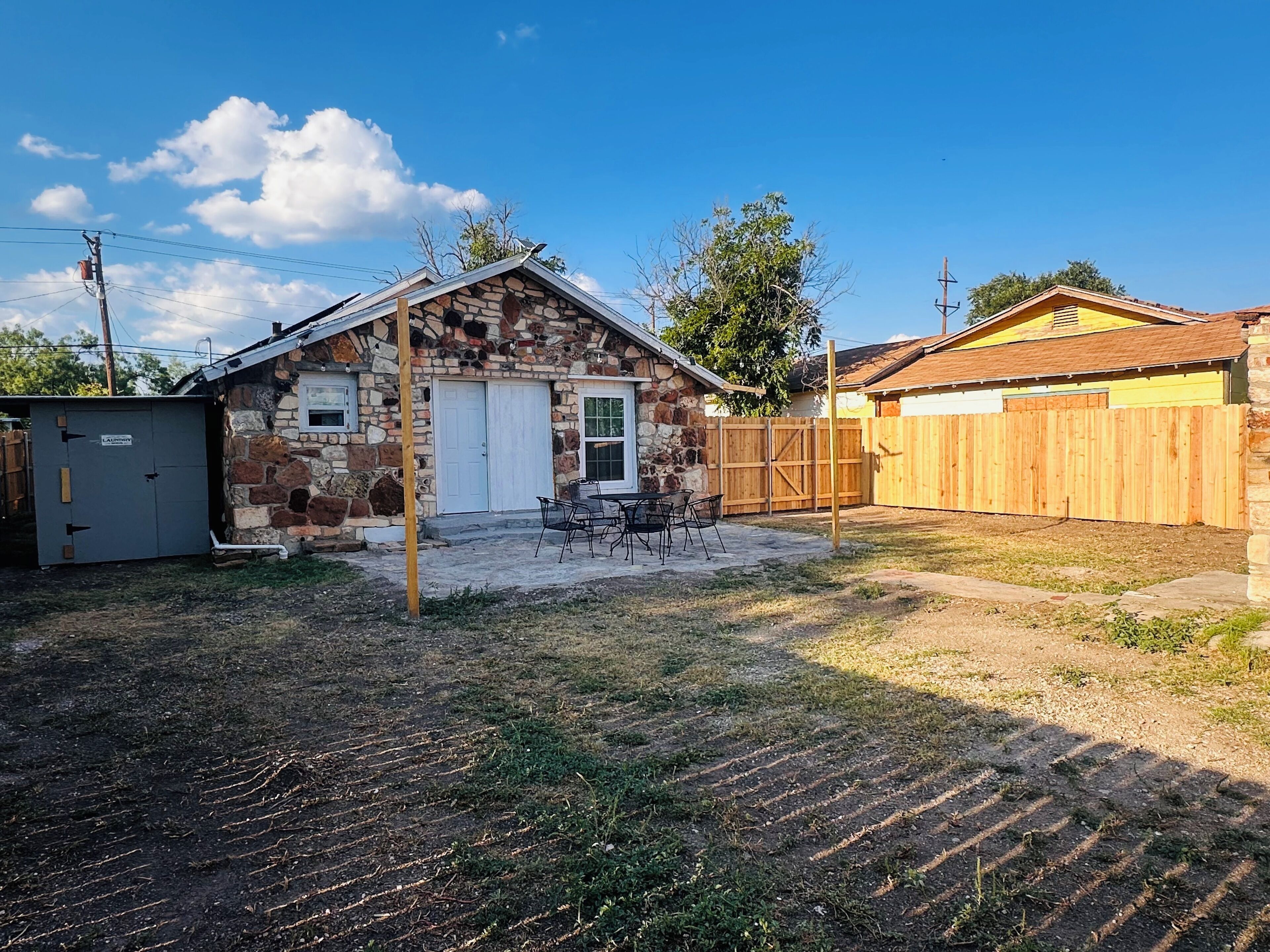 A stone house with a garage, a fenced yard, and a small patio area.