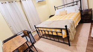 Un dormitorio con cama, escritorio, silla, ventilador de techo y cortinas.