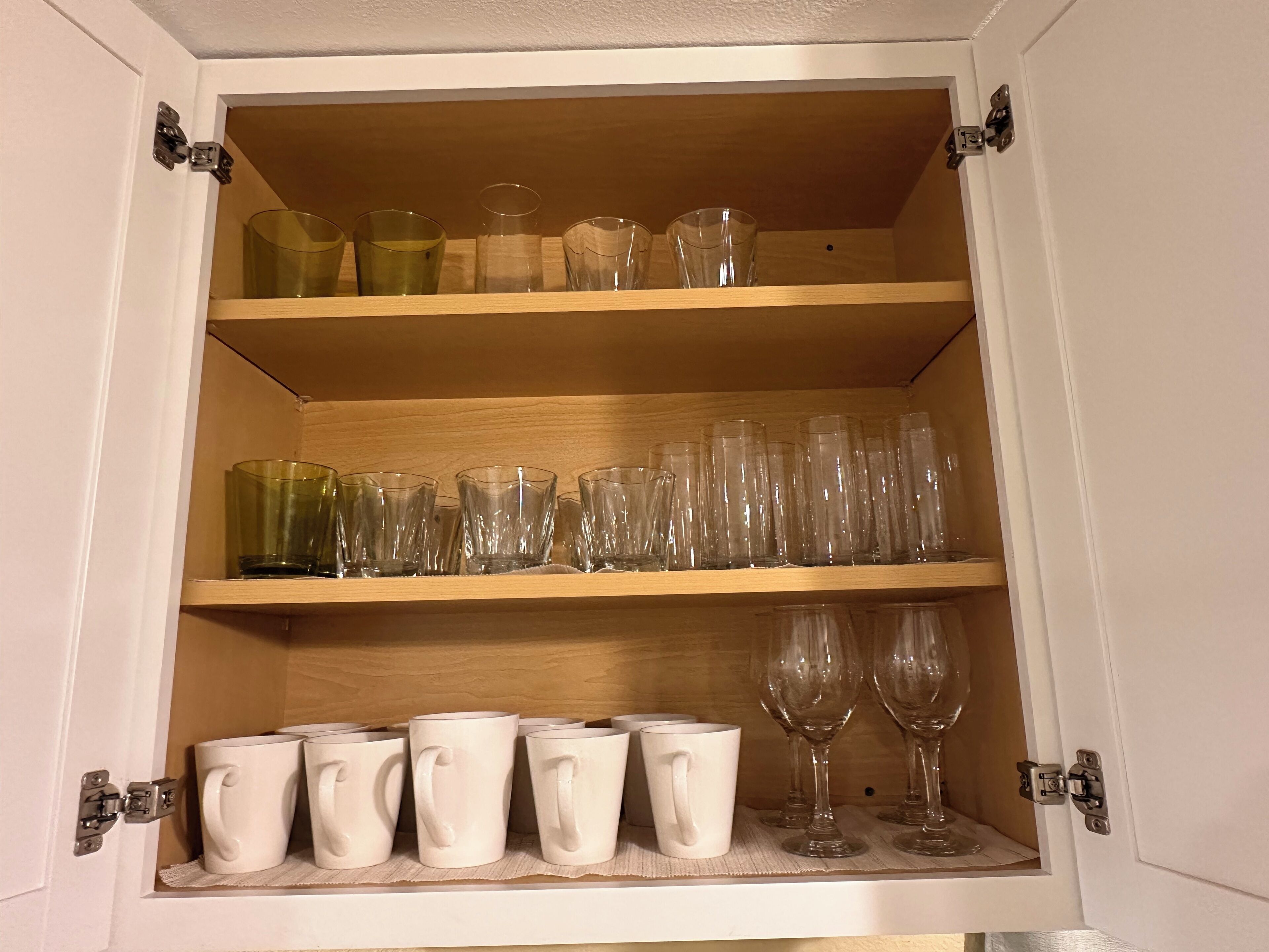 A cabinet with shelves containing various glassware and mugs.