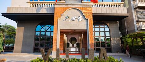 A building with a prominent entrance, large windows, and a sign with Chinese characters.