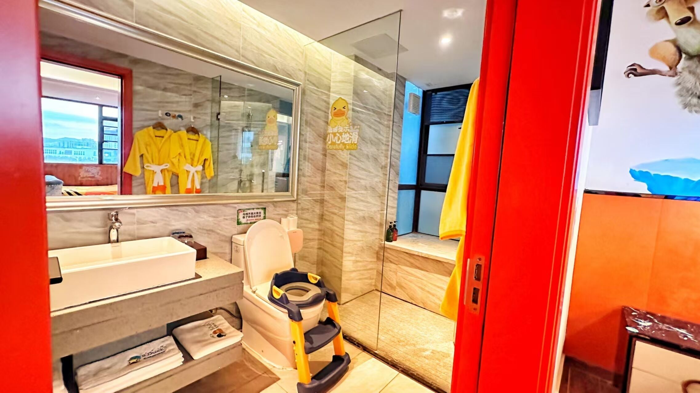 A modern bathroom with a marble wall, a sink, a toilet, and a shower area.