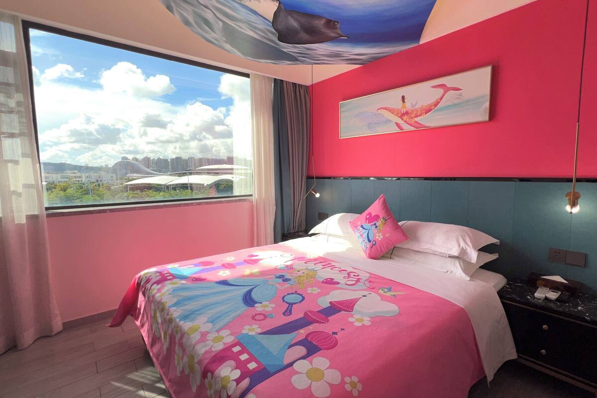 A hotel room with a large bed, a city view, a ceiling mural, and a painting on the wall.
