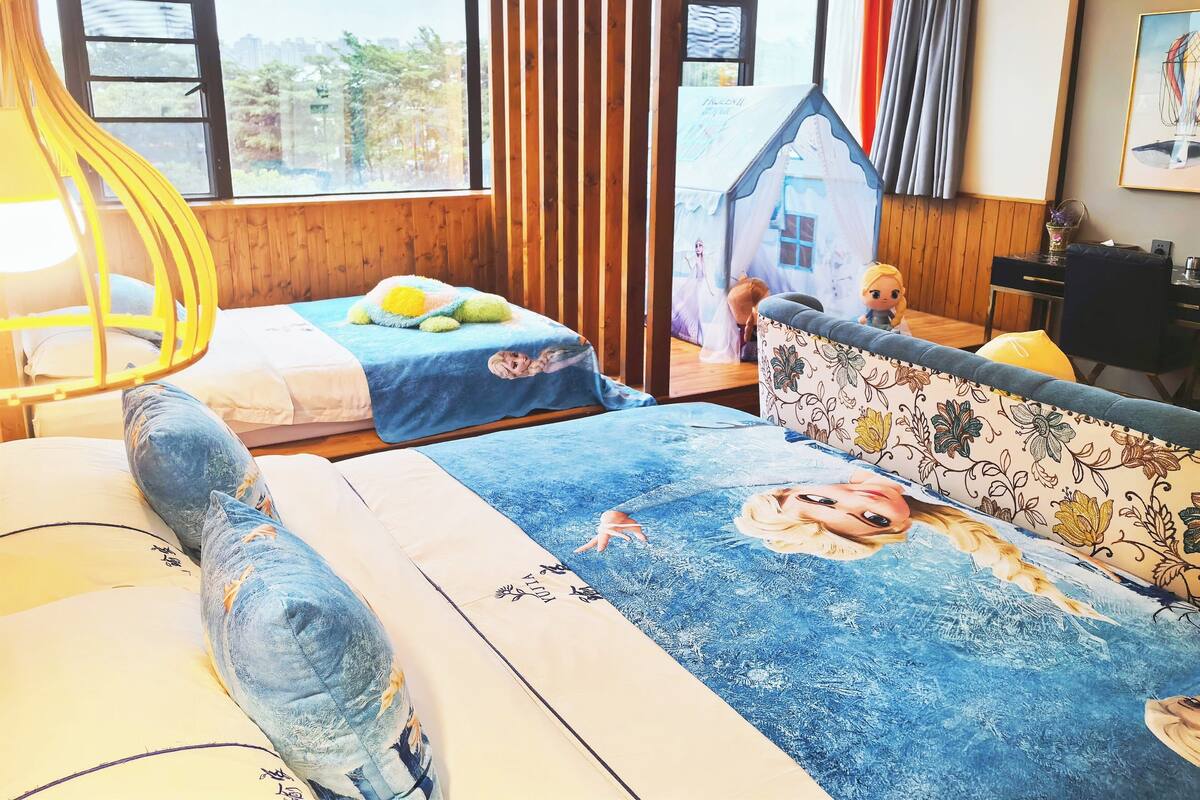 A bedroom with two beds, a window with a view, a wooden headboard, and a small house decoration on the wall.