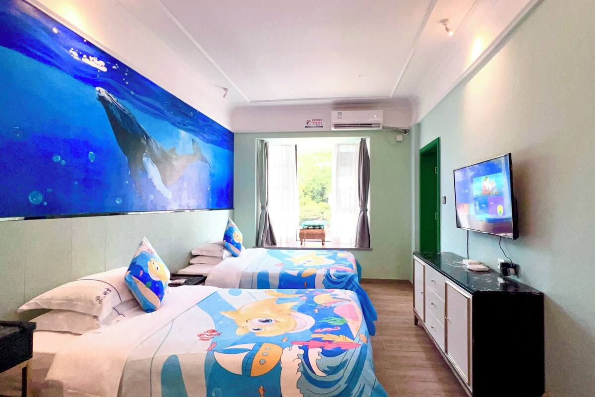 A hotel room with two beds, a large TV, a desk, and a window with curtains.