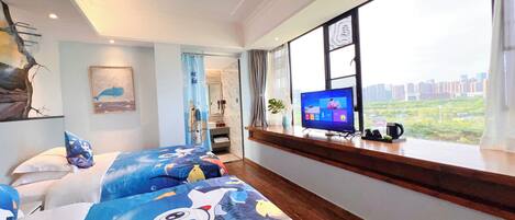 A hotel room with a large window, a bed with a colorful bedspread, a television on a wooden console, and a view of a cityscape.