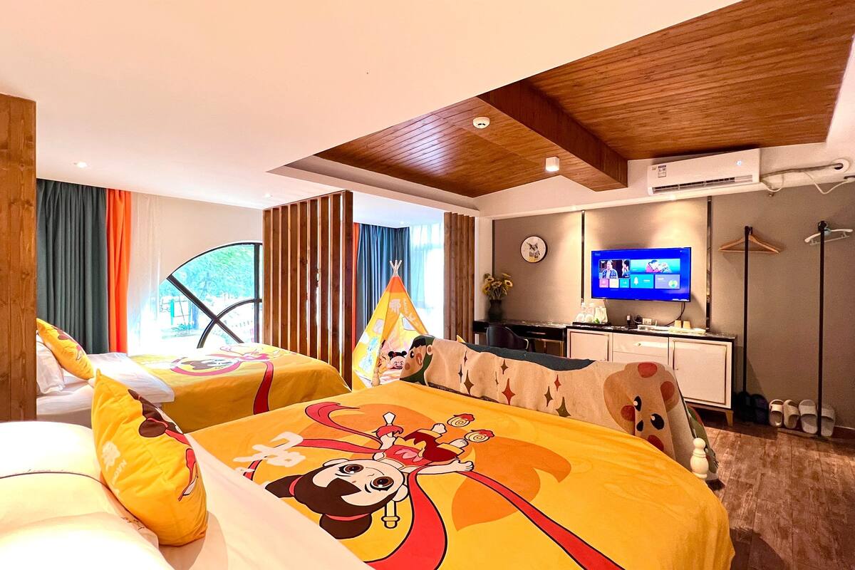A hotel room with two beds, a TV, a desk, and a shower area.