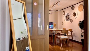 Una puerta de madera con paneles de vidrio satinado y un cartel de prohibido fumar. En el interior, hay una zona de comedor con una mesa de madera, sillas y decoración en la pared.