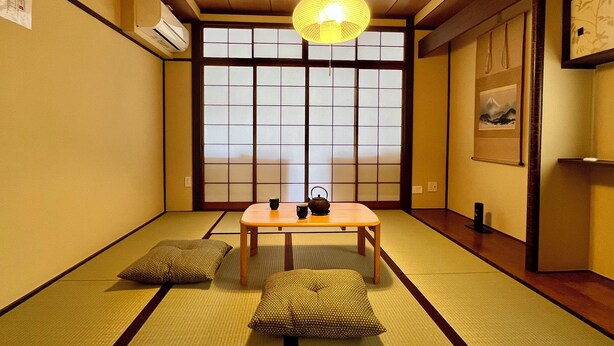 Una habitación japonesa tradicional con suelo de tatami, una mesa de madera baja y cojines.