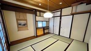 Una habitación japonesa tradicional con suelo de tatami, puertas correderas y una lámpara colgante.