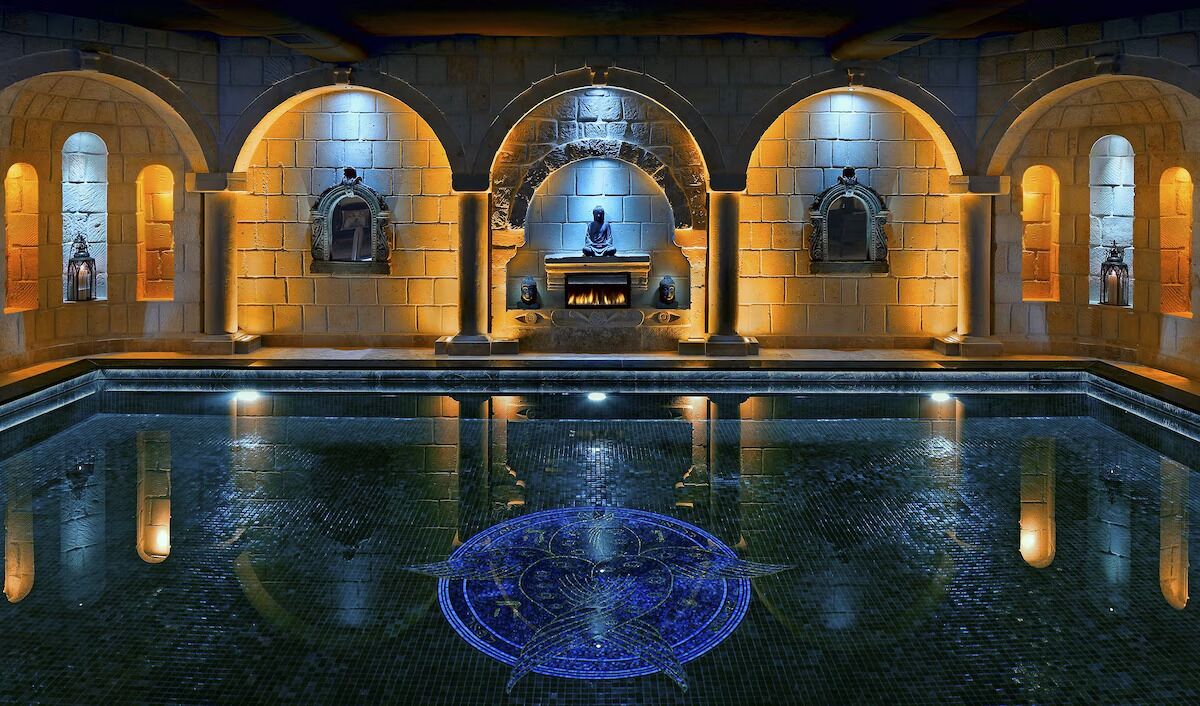 Sink into a tranquil pool beneath glowing arches and mosaics.