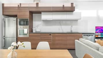 A modern kitchen with wooden cabinets, stainless steel appliances, and a dining area with a vase of flowers.