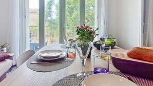 A dining area with a table set for two, a vase of flowers, and a bowl of salad. - La siesta by Interhome (Six Fours)