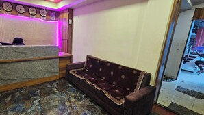 Ein Hotel-Empfangsbereich mit Empfangstresen, einer Couch und einer Uhr.