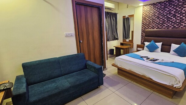 Ein Hotelzimmer mit einem großen Bett, einem blauen Sofa, einem Holfnachtkästchen und einer Wand mit Muster.