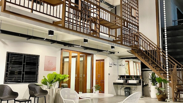 A two-story building with a wooden balcony, a staircase, and a seating area with chairs and a table. - Secret Corner Boutique Stay  (Chiang Rai)