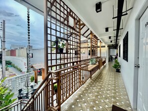 A corridor with a wooden railing, potted plants, and a tiled floor. - Secret Corner Boutique Stay  (Chiang Rai)