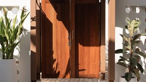 A wooden double door with a metal handle, flanked by potted plants on either side. - Secret Corner Boutique Stay  (Chiang Rai)