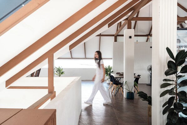 Un interior moderno con una escalera de madera, un comedor con sillas y plantas en macetas.