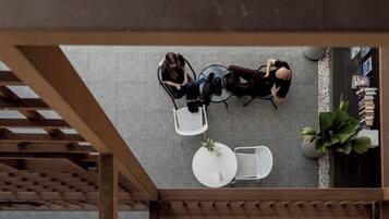 An overhead view of a café with a wooden pergola, white chairs, and a round table.