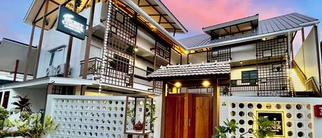 A two-story building with a balcony, a signboard, and a gated entrance.