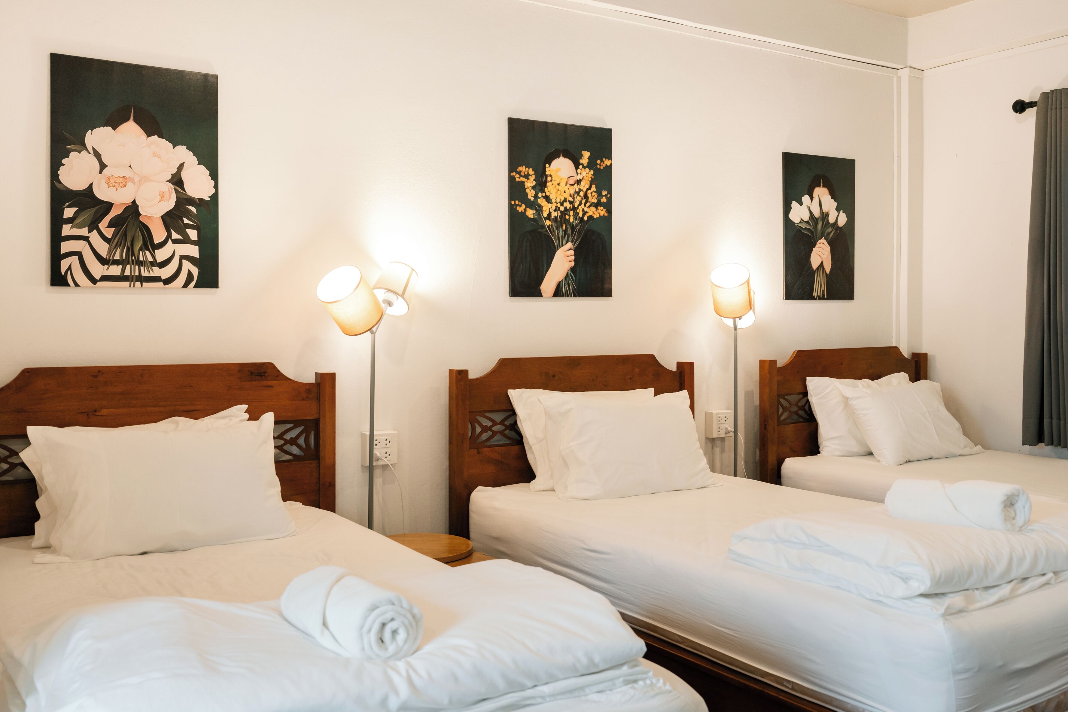 A hotel room with two beds, white linens, and artwork on the walls.