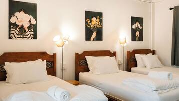 A hotel room with two beds, white linens, and artwork on the walls.