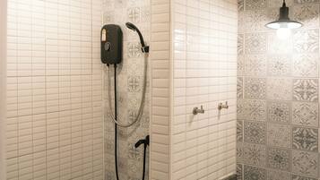Un baño con ducha, un cabezal de ducha de mano, un panel de control en la pared y un diseño de azulejos estampados.