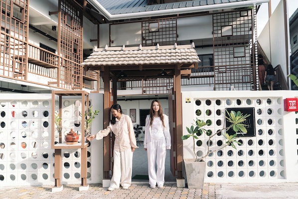 A traditional building with a tiled roof, a wooden structure with a tiled roof, and a white wall with circular cutouts.
