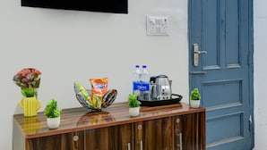 Um armário de madeira com uma televisão de tela plana montada acima, uma porta azul e um pequeno vaso de plantas sobre o armário.