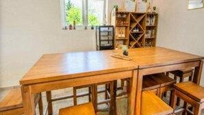 A wooden dining table with benches, a bookshelf, and a window with a view of greenery. - Rooms Burnum (Biskupija)