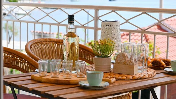 A balcony table with a bottle, glasses, a vase, and pastries. - Apartment Zara (Marina)