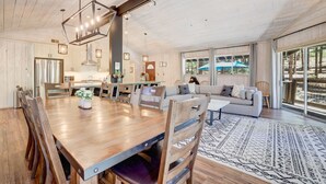 A spacious living area with a wooden dining table, sofas, and a large window offering a view of the outdoors. - Family Retreat | Master Suites-Hot Tub | Sleeps10 (Stateline)