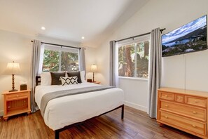 A bedroom with a large bed, two bedside tables with lamps, a dresser, and a large window with curtains. - Family Retreat | Master Suites-Hot Tub | Sleeps10 (Stateline)