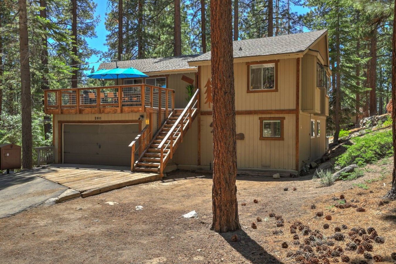 A two-story cabin with a garage and a wooden deck.