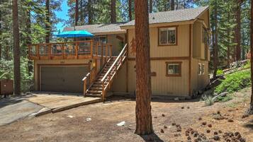 A two-story cabin with a garage and a wooden deck.