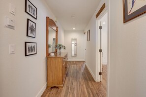A hallway with wooden flooring, a wooden dresser, and framed pictures on the walls.