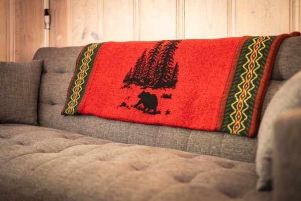 A sofa with a blanket featuring a forest and animal silhouette.