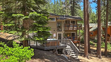 A two-story lodge with a deck and stairs leading to the entrance.