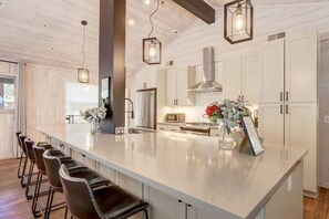 A modern kitchen with a large island, bar stools, and pendant lighting.