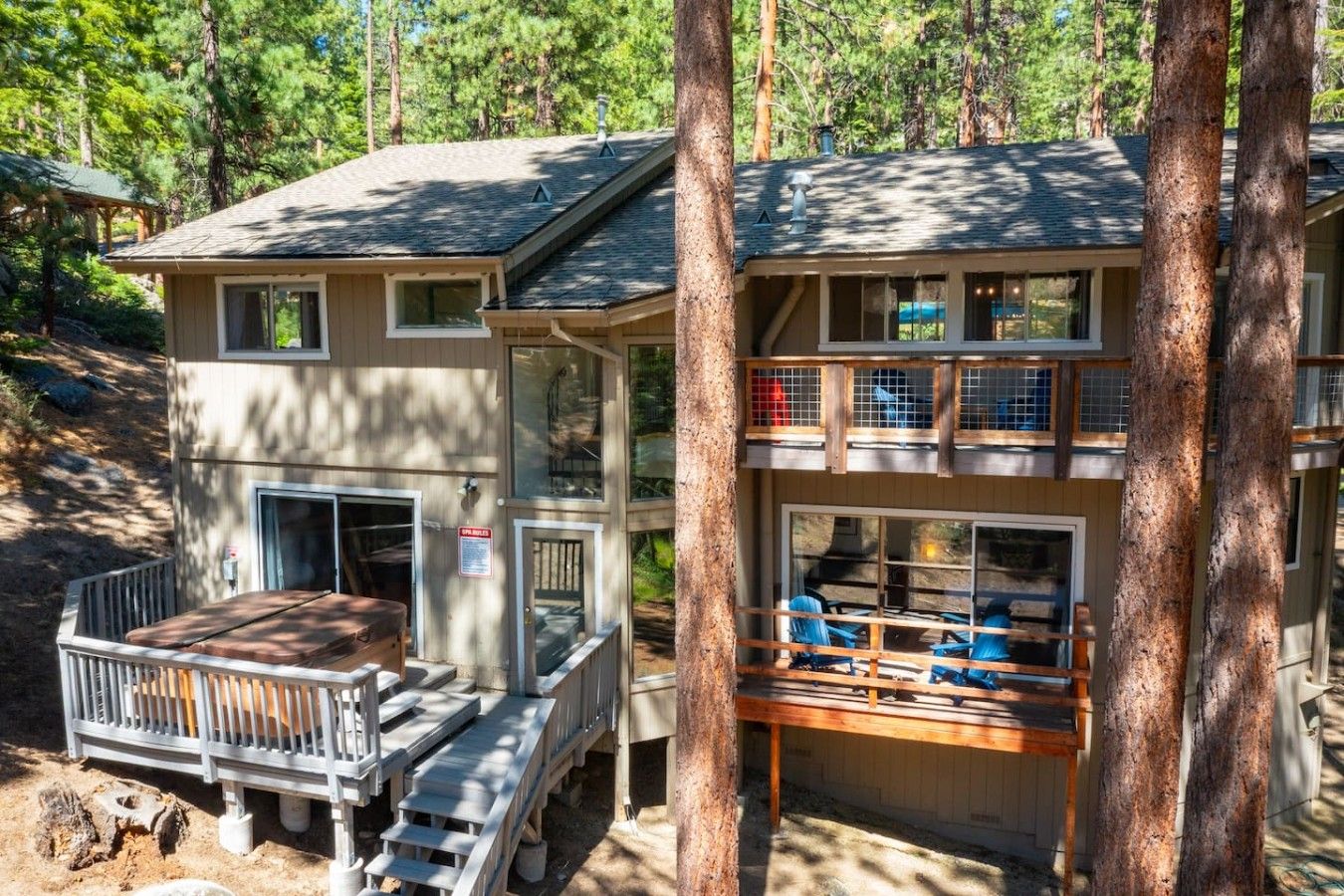 Eine zweistöckige Hütte mit einer Terrasse und einer überdachten Sitzgruppe im Freien.