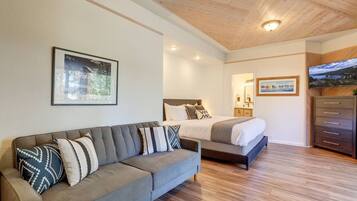 A modern bedroom with a bed, a sofa, a dresser, and two framed pictures on the wall.