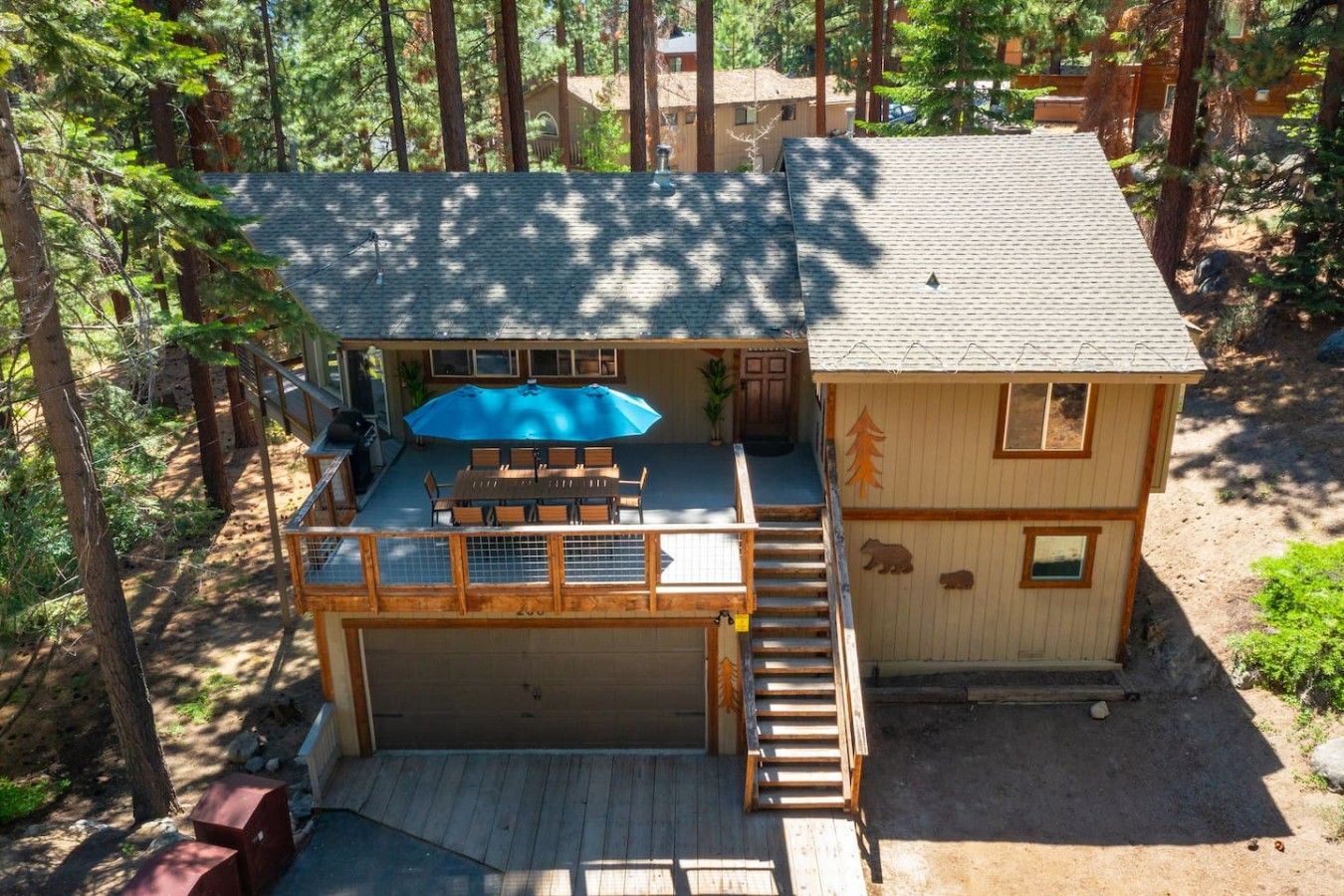 A two-story cabin with a deck, a covered patio, and a garage.