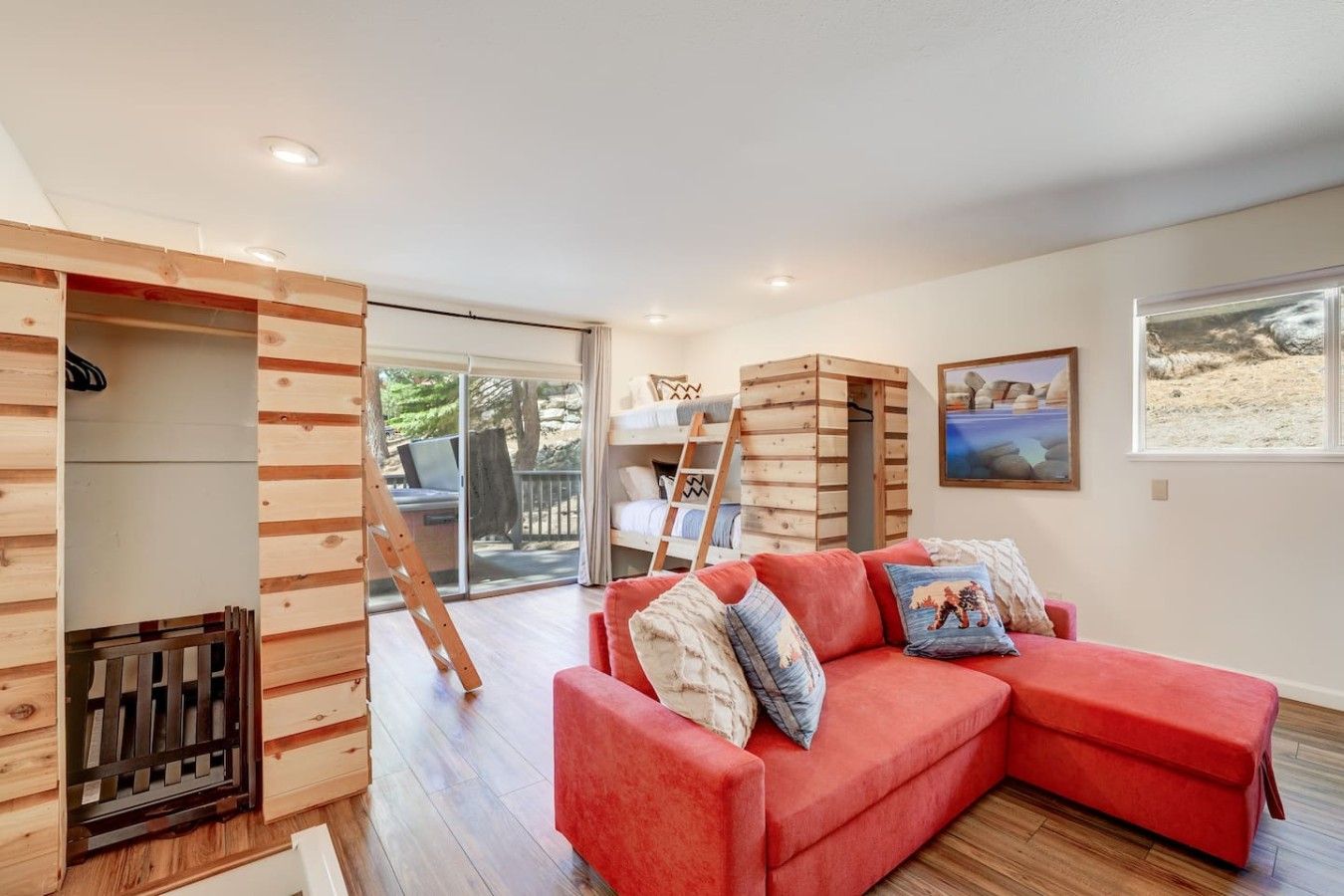 A room with a red sofa, wooden bunk beds, and a view of the outdoors.