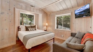 A bedroom with a bed, two windows, a TV, and a sofa. - Family Retreat | Master Suites-Hot Tub | Sleeps10 (Stateline)