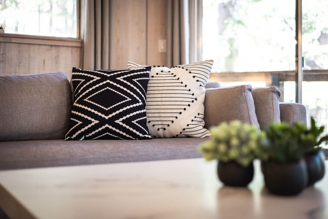 Ein Sofa mit gemusterten Kissen und einem Blumentopf auf einem Tisch.