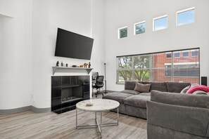 A modern living room with a fireplace, a flat-screen TV, a sofa, and a coffee table.