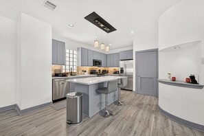 A modern kitchen with grey cabinets, stainless steel appliances, and a central island with bar stools.