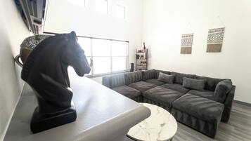 A modern living room with a sectional sofa, a marble coffee table, and a horse sculpture on a counter.